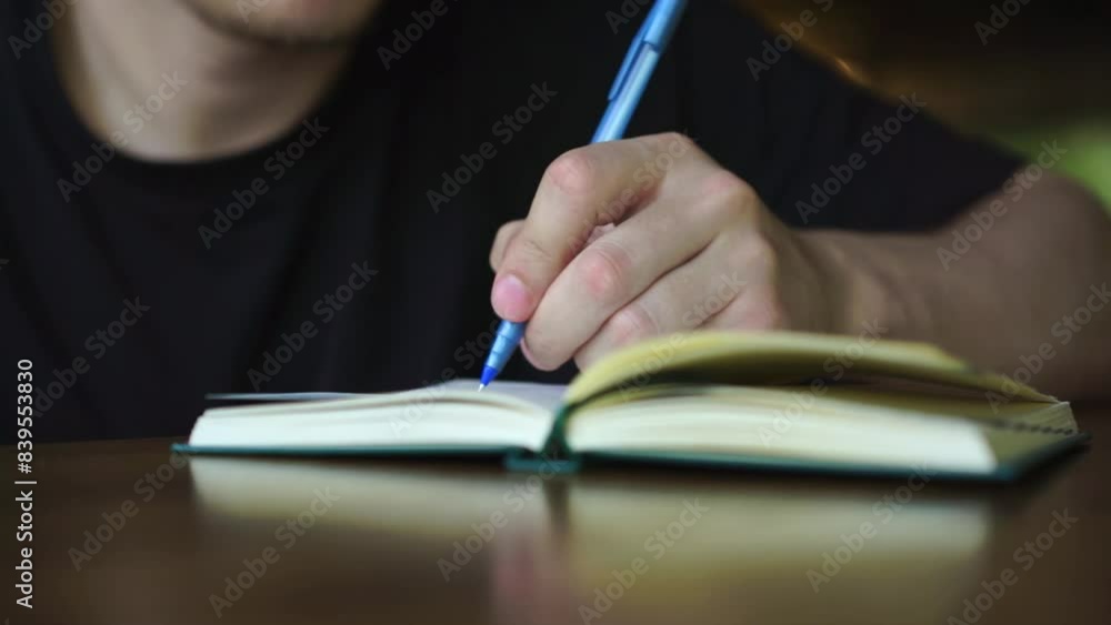 a man writes with a blue pen in a notepad.
Man with pen and notepad sitting at table a man writes with a blue pen in a notepad.
Man with pen and notepad sitting at table