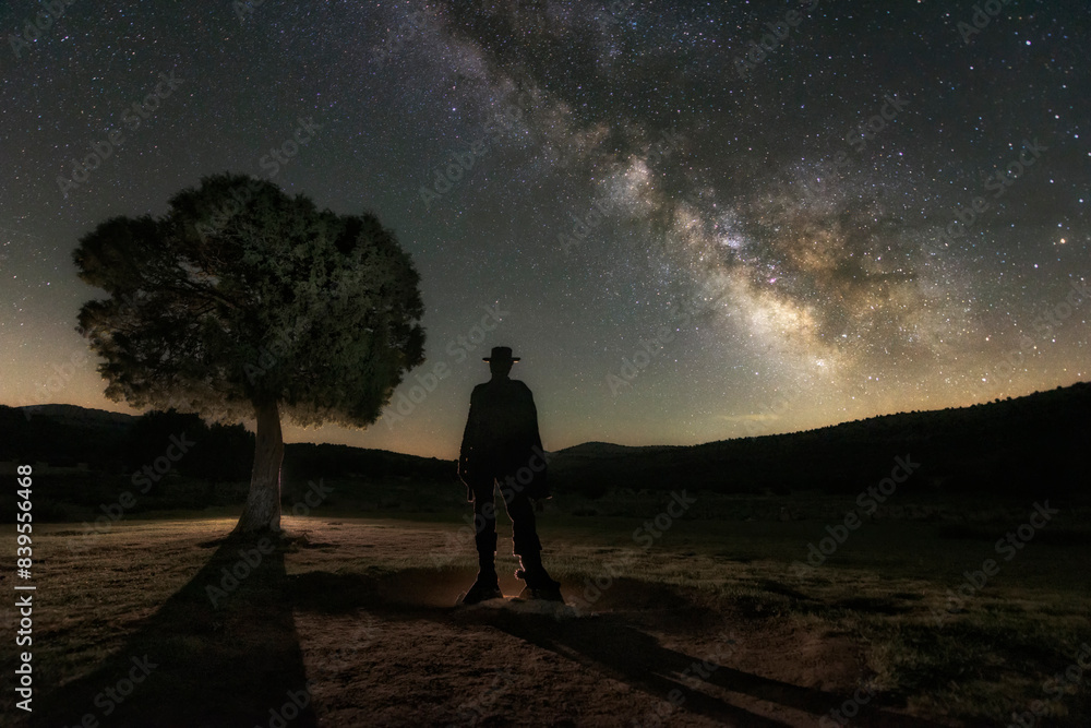 Cowboy silhouette looks towards the Milky Way on a starry night at Sad Hill Cemetery, film location