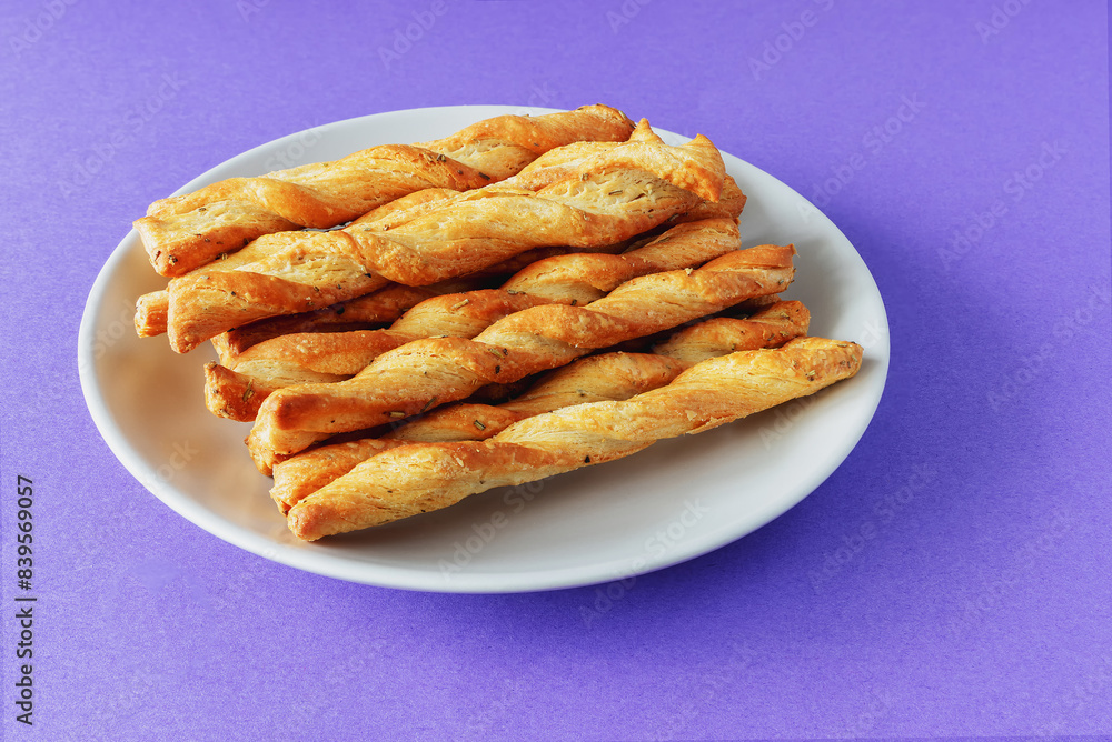 Sticks of buttery yeast dough on a plate on a purple background Sticks of buttery yeast dough on a plate on a purple background