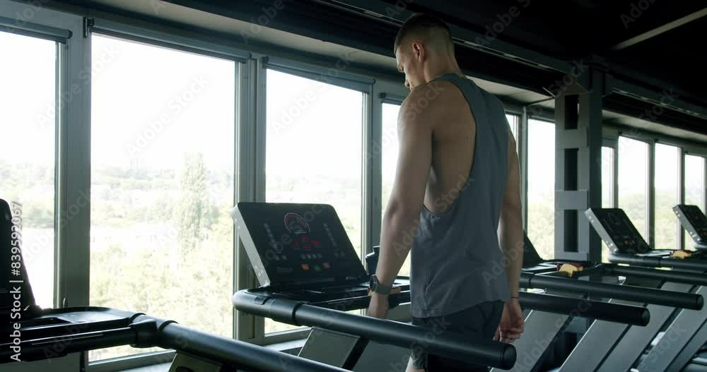 A young athletic male jogging on a treadmill in a well-equipped gym overlooking a scenic urban landscape. Capturing fitness and lifestyle balance. Fit Young Man Running on Treadmill in Modern Gym A young athletic male jogging on a treadmill in a well-equipped gym overlooking a scenic urban landscape. Capturing fitness and lifestyle balance. Fit Young Man Running on Treadmill in Modern Gym