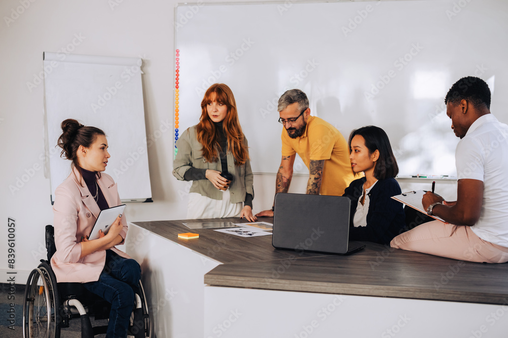 © Zamrznuti tonovi - Woman with disability discussing the business strategy with her diverse team © Zamrznuti tonovi - Woman with disability discussing the business strategy with her diverse team