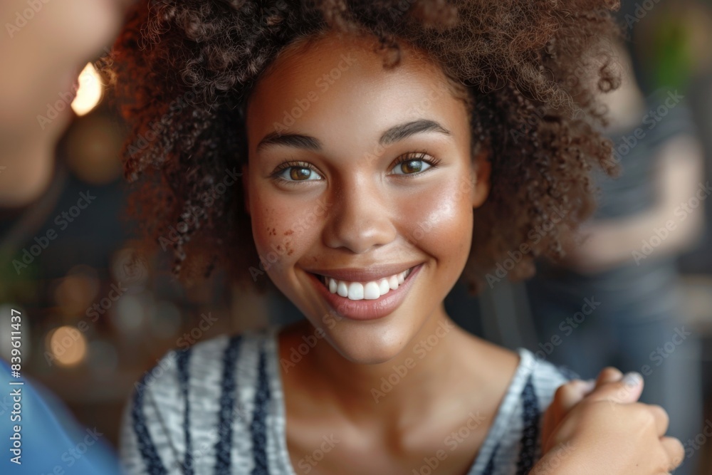 Curly-haired woman in blue shirt smiles at camera Curly-haired woman in blue shirt smiles at camera