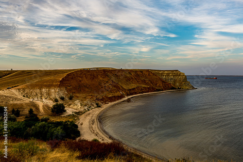 White Cirrus clouds in the blue sky on the Alexander graben. Steep cliff on the bank of the Volga River (Volgograd, Russia). Red clay, yellow sand on the beach, steep walls of the ravine.