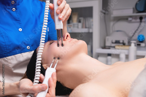 Close-up of a woman receiving an electric neck massage with equipment in a beauty salon. Used for therapy with a multifunctional electro massage device photo