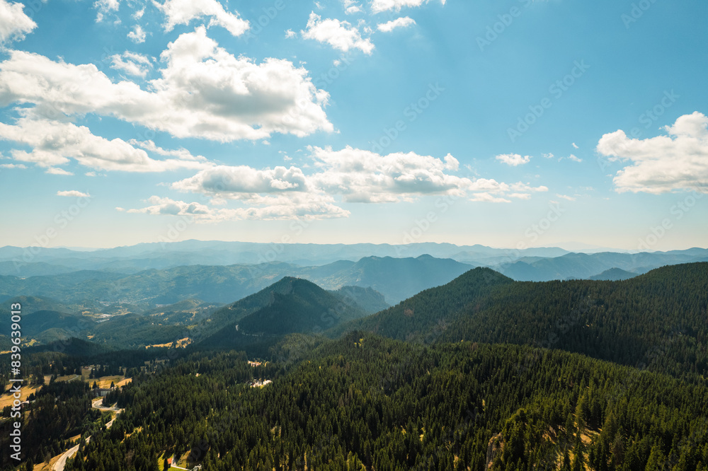 Fototapeta premium Panorama of beautiful nature aerial view white clouds, blue sky, horizon, mountains, pine forest and meadows. Nature. Relax