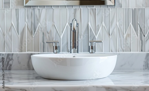 A closeup shot of the modern white sink with chrome faucet  centered on an elegant marble countertop in