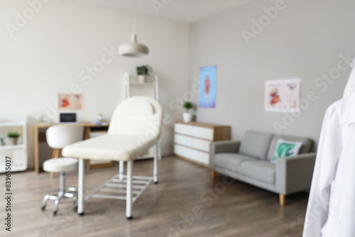 Blurred view of medical office with couch, sofa and doctor's workplace