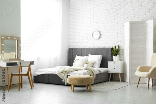 Cozy bed  pillows and pouf in beautiful bedroom