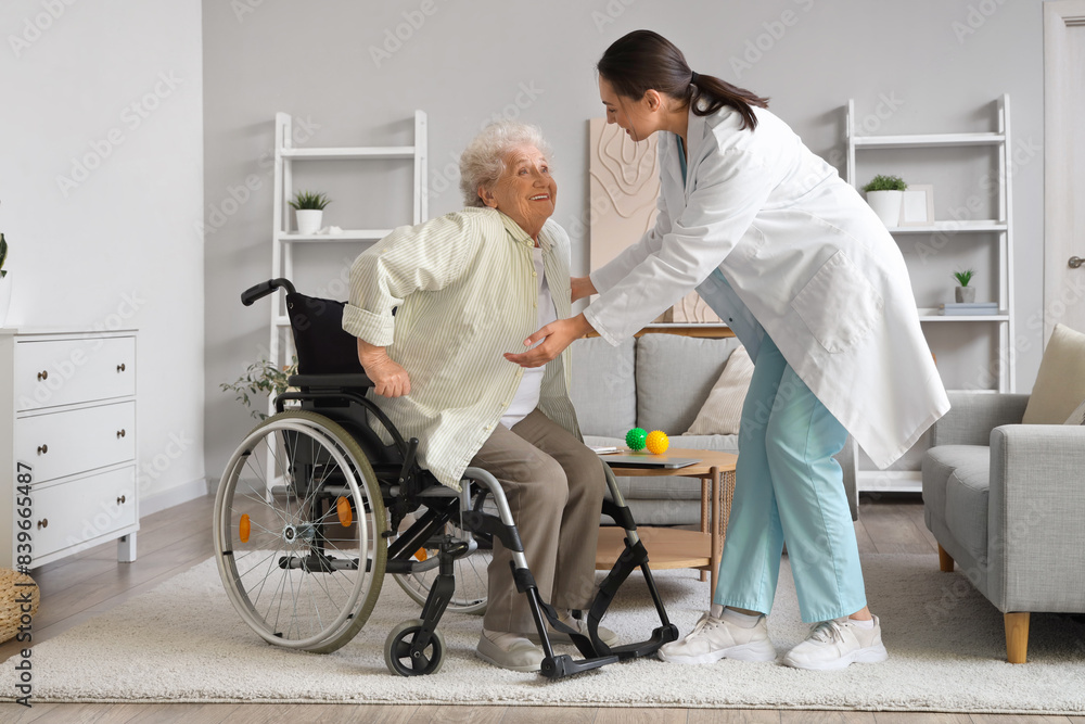 Physical therapist helping senior woman to stand up from wheelchair at home Physical therapist helping senior woman to stand up from wheelchair at home