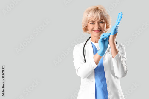 Female doctor putting glove...
