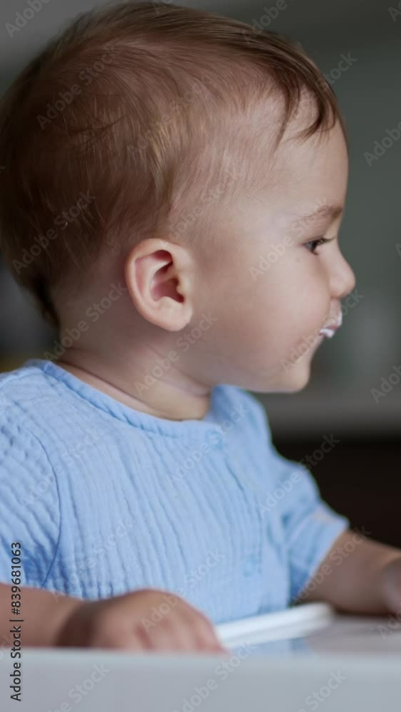 Adorable baby boy eating porridge from spoon. Caring mother giving food to her son. Side view. Blurred backdrop. Vertical video Adorable baby boy eating porridge from spoon. Caring mother giving food to her son. Side view. Blurred backdrop. Vertical video