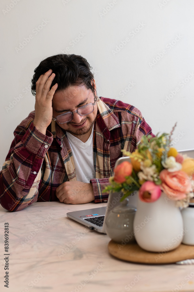 Young man with headache with his laptop in the living room making pain gesture Young man with headache with his laptop in the living room making pain gesture