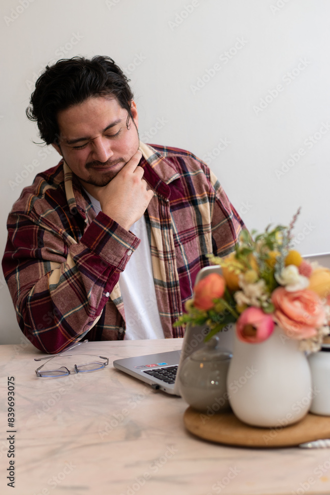 Young man with headache with his laptop in the living room making pain gesture Young man with headache with his laptop in the living room making pain gesture