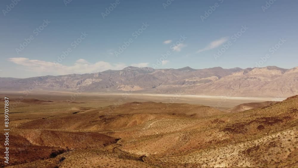 A drone takeoff captures an aerial view of the Mojave Desert's expansive landscape, showcasing geological formations, a winding dirt trail, and. wilderness. The drone flies above, revealing the dry A drone takeoff captures an aerial view of the Mojave Desert's expansive landscape, showcasing geological formations, a winding dirt trail, and. wilderness. The drone flies above, revealing the dry