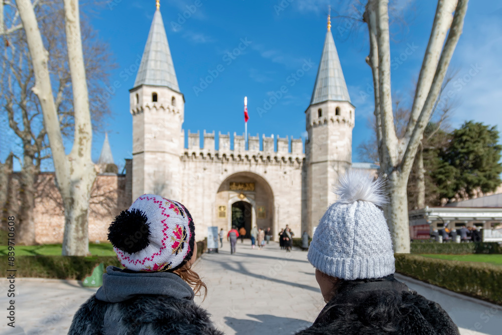 Obraz premium Mother and daughter with hats in the winter walking in the park and looking at the castle.