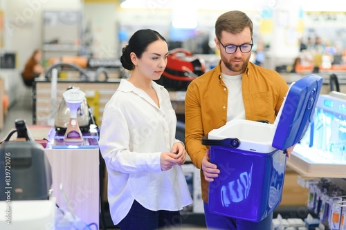 A young couple buys a portable refrigerator in an electronics store photo