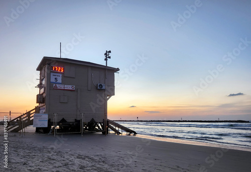 Sunset on sandy beach with calm sea and rescue booth