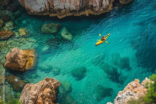 View from the rock cliffs of kayaker exploring the crystal clear Mediterranean waters of a cove off the coast of Dubrovnik, Croatia