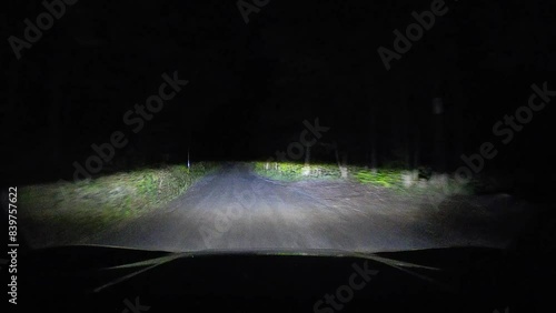 Night driving on country road driving view dark night through forest with headlights only. Wilderness rural lane while travelling. Moving through gravel dirt road in a rocky off-road driver pov. photo