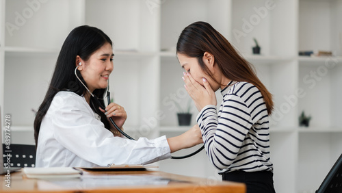 Female doctor using a stethoscope to examine a young patient in a modern clinic. Medical consultation and healthcare service.