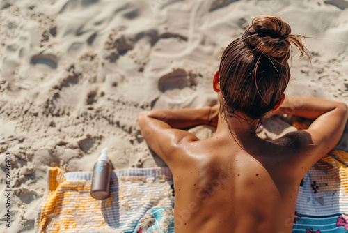 Woman sunbathing on the sand on the beach on her vacation trip, lying face down with her back tanning, enjoying a relaxing summer trip by the sea