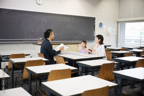面談を受ける親と子供　小学校の教室での三者面談のイメージ photo