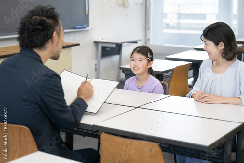 面談を受ける親と子供　小学校の教室での三者面談のイメージ photo