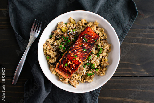 Seared Salmon with Mushroom Risotto in a Pasta Bowl: Marinated salmon fish fillet on a bed of mushroom risotto with scallions and sesame seed garnish