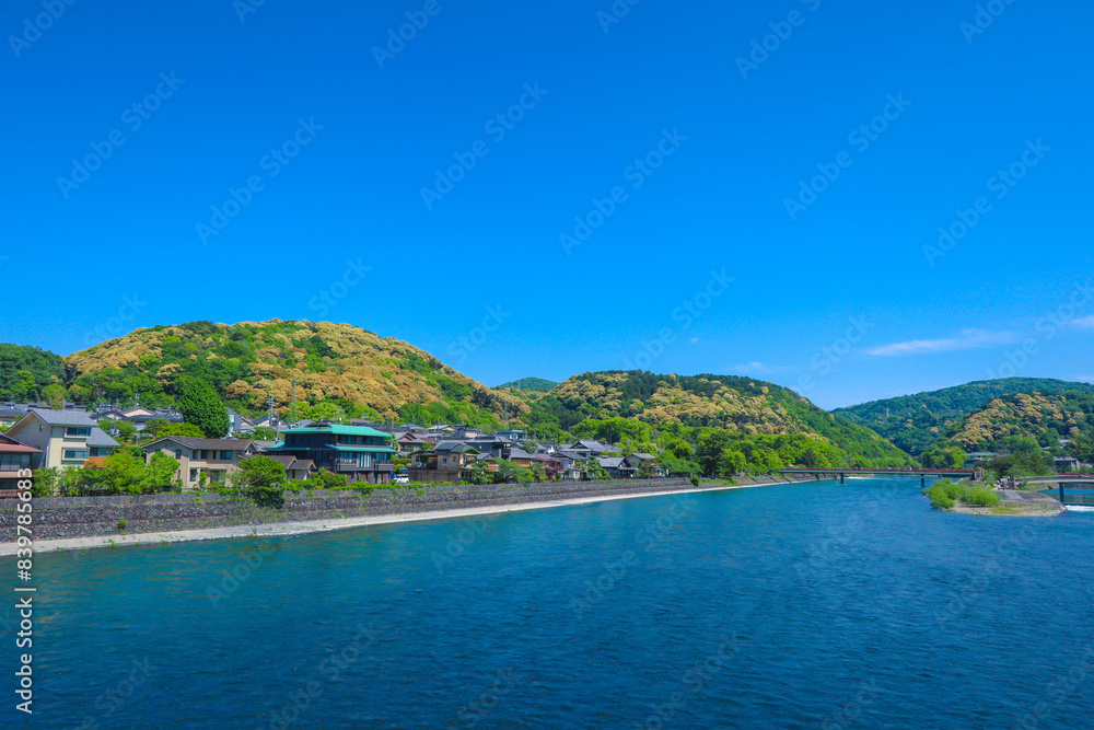 A river surrounded by trees and traditional houses in Japan with hills background A river surrounded by trees and traditional houses in Japan with hills background