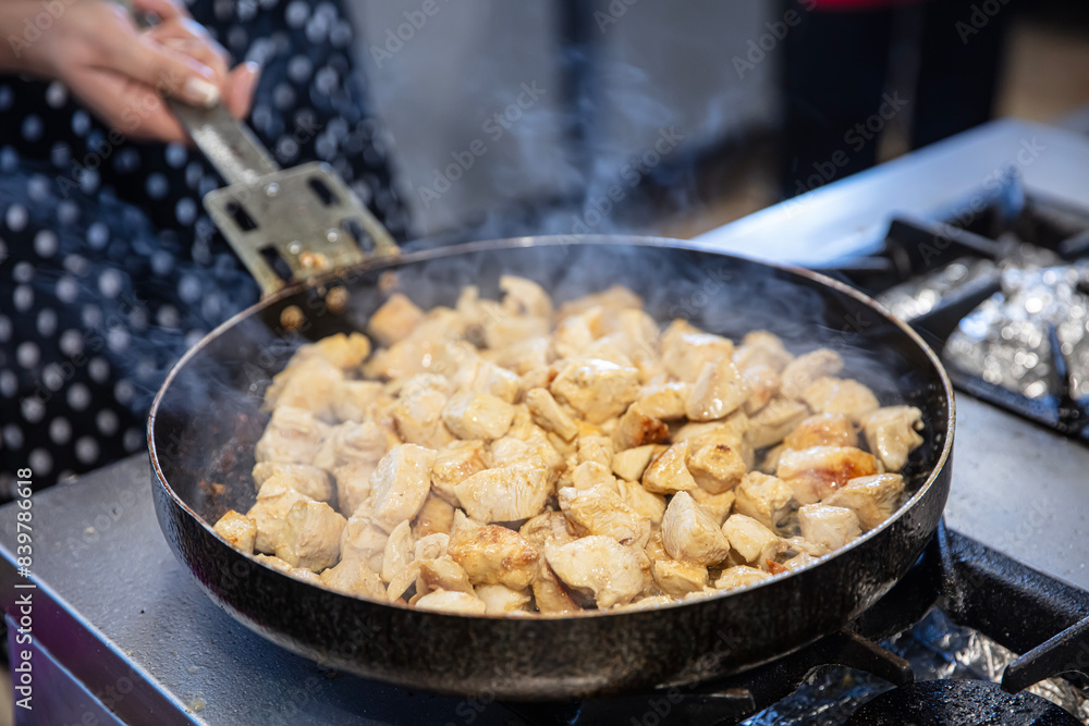 Chef preparing creamy chicken saute in the kitchen. Female cook prepares chicken saute in a large pan in the kitchen of the restaurant. Chef preparing creamy chicken saute in the kitchen. Female cook prepares chicken saute in a large pan in the kitchen of the restaurant.
