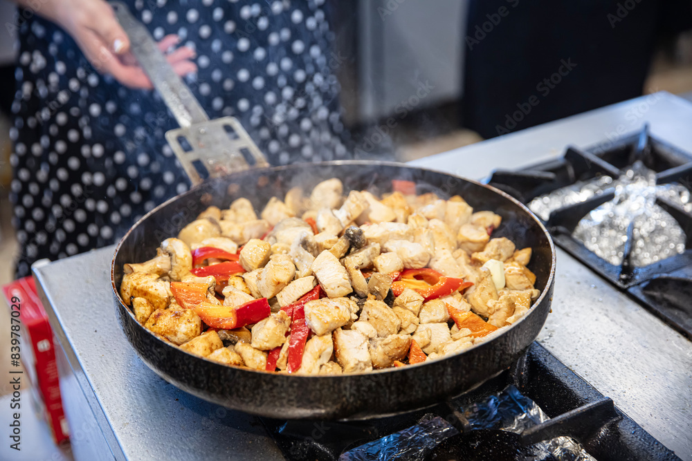 Chef preparing creamy chicken saute in the kitchen. Female cook prepares chicken saute in a large pan in the kitchen of the restaurant. Chef preparing creamy chicken saute in the kitchen. Female cook prepares chicken saute in a large pan in the kitchen of the restaurant.
