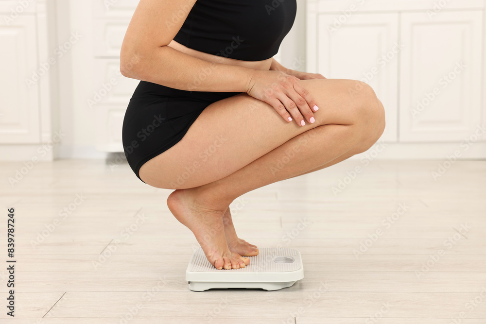 Fototapeta premium Woman standing on floor scales indoors, closeup