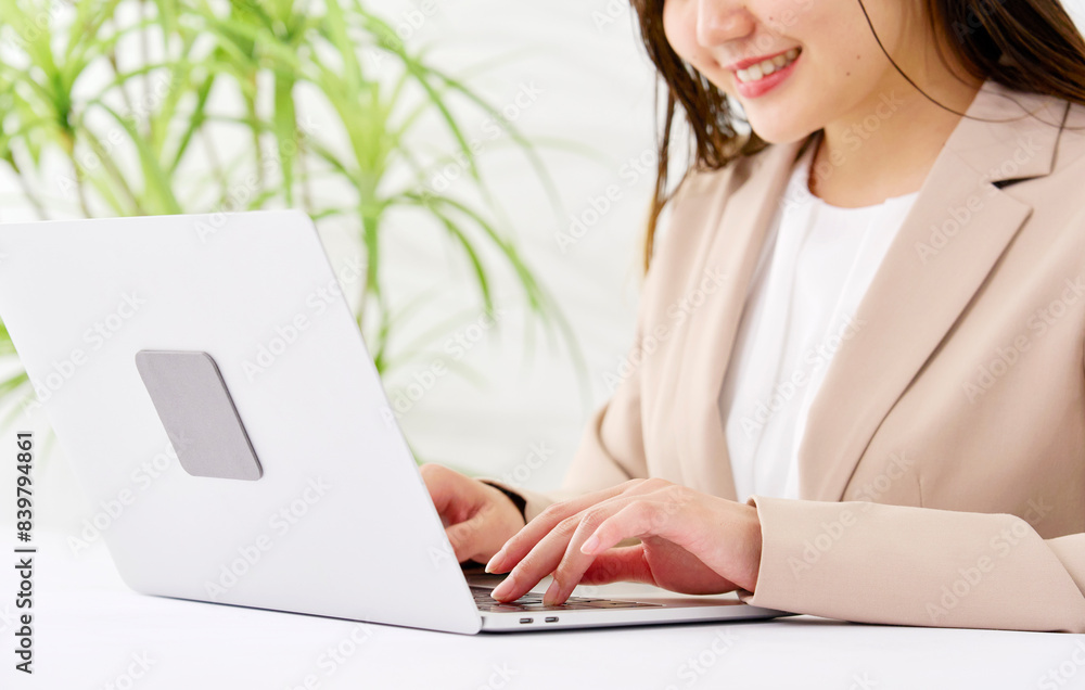 オフィスでパソコンを使ってデスクワークをする若いビジネスウーマン　顔無し