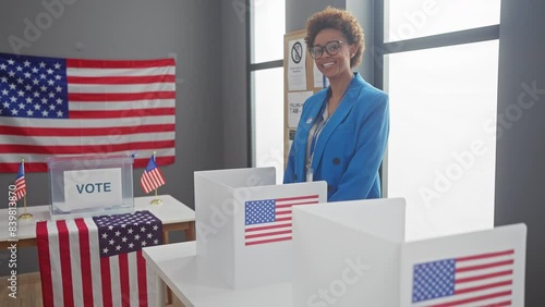 African american woman voting in a booth at a us electoral center with american flags. photo