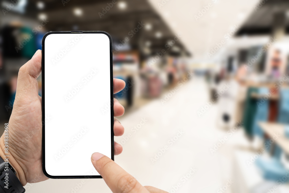 Hand holding blank screen smartphone for copy space on blurred clothing store. e-commerce app shopping mockup. social media, payment and shopping online concept. fashion and technology. Hand holding blank screen smartphone for copy space on blurred clothing store. e-commerce app shopping mockup. social media, payment and shopping online concept. fashion and technology.