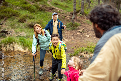 Multi-generational family crossing a stream during a forest hike photo