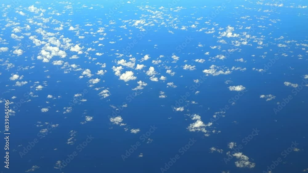 Airplane flying high above the clouds with the sea below. Plane flying above the clouds with blue ocean below. Plane window view. Air transportation. Airplane flying high above the clouds with the sea below. Plane flying above the clouds with blue ocean below. Plane window view. Air transportation.