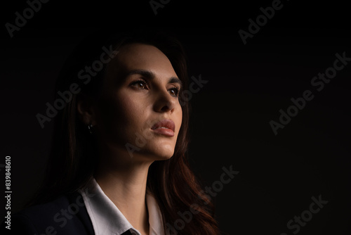 A woman in a suit and tie is looking up in the dark