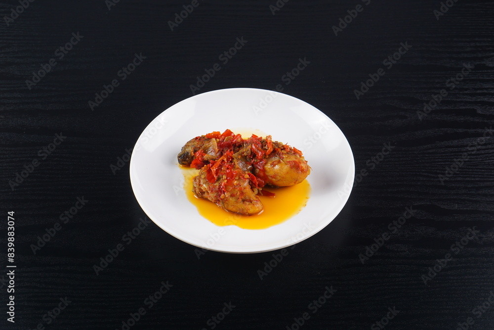 Indonesian typical balado fried chicken on a white plate on a black background with studio lighting Indonesian typical balado fried chicken on a white plate on a black background with studio lighting