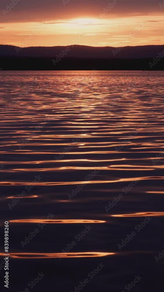 A fiery sunset on the lake with a mirror reflection of light on the water. Picturesque view of the lake. Beauty is in nature. Vertical video, shorts. A fiery sunset on the lake with a mirror reflection of light on the water. Picturesque view of the lake. Beauty is in nature. Vertical video, shorts.