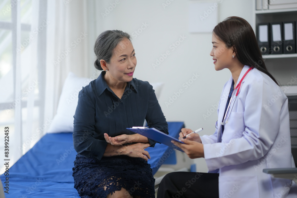 Obraz premium Doctor discussing medical condition with an elderly woman in a hospital room, engaging in a friendly conversation.
