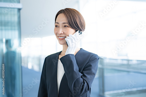 携帯で連絡をする白い手袋をつけスーツを着た日本人女性