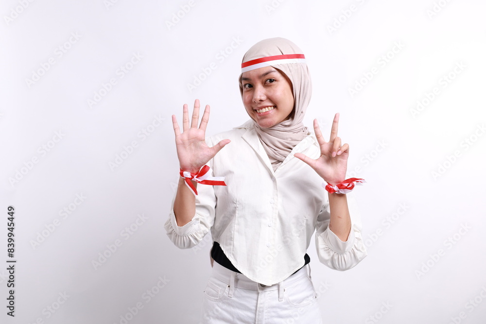 Asian young asian muslim woman with red white ribbon for celebrating Indonesia independence day standing while showing eight fingers Asian young asian muslim woman with red white ribbon for celebrating Indonesia independence day standing while showing eight fingers