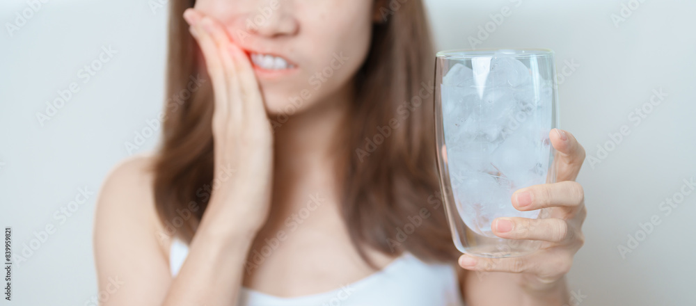 Teeth Sensitive to Cold concept. woman hold Ice Water glass and having toothache and pain after eat. Tooth Decay or Gum Disease, Grinding Teeth and Stress, Exposed Nerve Roots, Crack and Receding Gums Teeth Sensitive to Cold concept. woman hold Ice Water glass and having toothache and pain after eat. Tooth Decay or Gum Disease, Grinding Teeth and Stress, Exposed Nerve Roots, Crack and Receding Gums