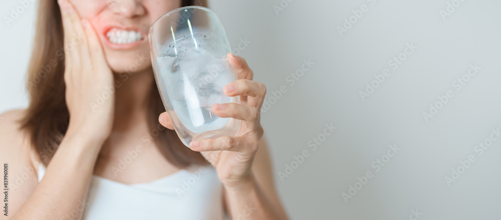 Teeth Sensitive to Cold concept. woman hold Ice Water glass and having toothache and pain after eat. Tooth Decay or Gum Disease, Grinding Teeth and Stress, Exposed Nerve Roots, Crack and Receding Gums Teeth Sensitive to Cold concept. woman hold Ice Water glass and having toothache and pain after eat. Tooth Decay or Gum Disease, Grinding Teeth and Stress, Exposed Nerve Roots, Crack and Receding Gums