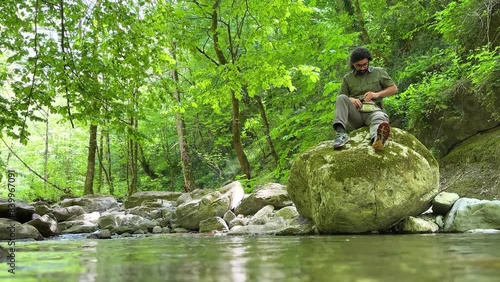 wonderful shallow water view of a man sit on a big rock in forest Hyrcanian nature spring season riverside mountain river scenic nature landscape in Azerbaijan travel guide tourism landmark in Iran photo