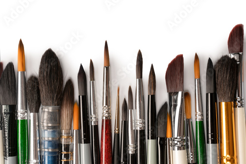 Mix of paint brushes in a row isolated on a white background. Top view.