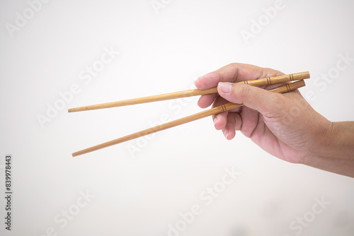 A woman’s hand is holding a set of chopstick photo