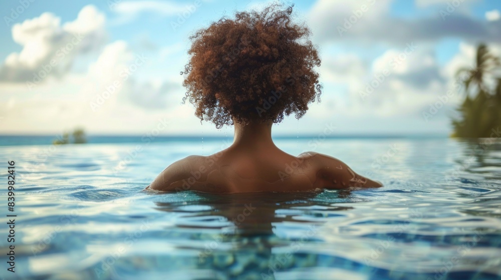 Close-up rear view of an African woman's head above water in a tropical pool setting, showcasing her curly hair and tranquil environment. Close-up rear view of an African woman's head above water in a tropical pool setting, showcasing her curly hair and tranquil environment.