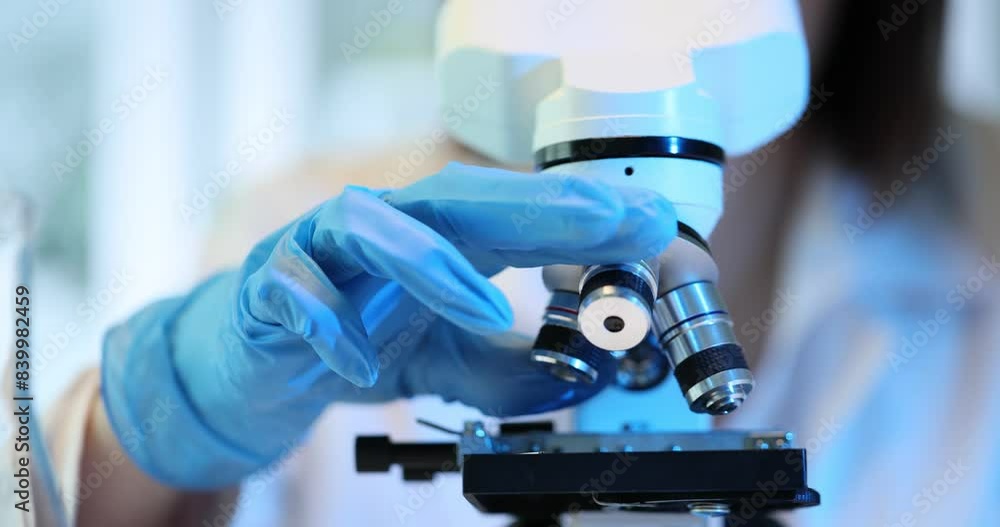Scientist uses a microscope to examine a sample in laboratory Scientist uses a microscope to examine a sample in laboratory